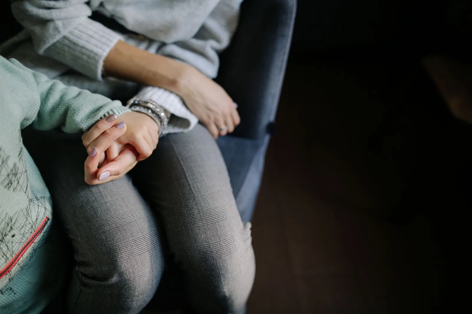 Un adult ține mâna unui copil, așezați unul lângă altul.